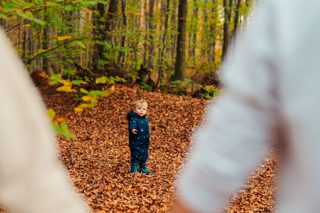 Enfant accompagné de ses parents sur un chemin forestier en automne