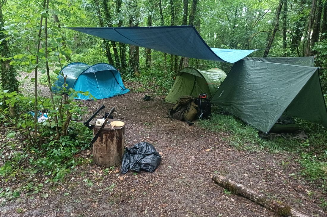 Camp de bivouac avec tentes et abris en forêt