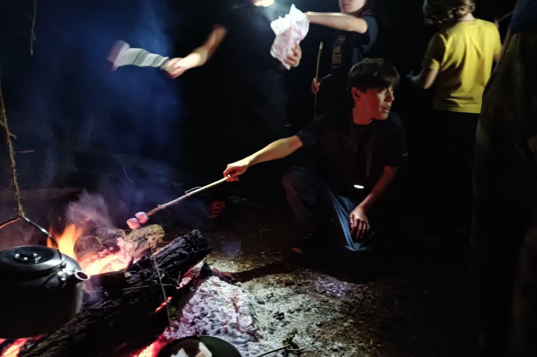 Préparation d'un repas au-dessus des braises à la nuit tombée