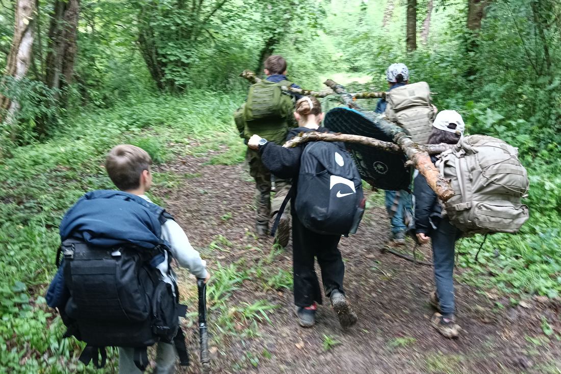 Groupe progressant en forêt avec sacs à dos lors d'un stage de survie